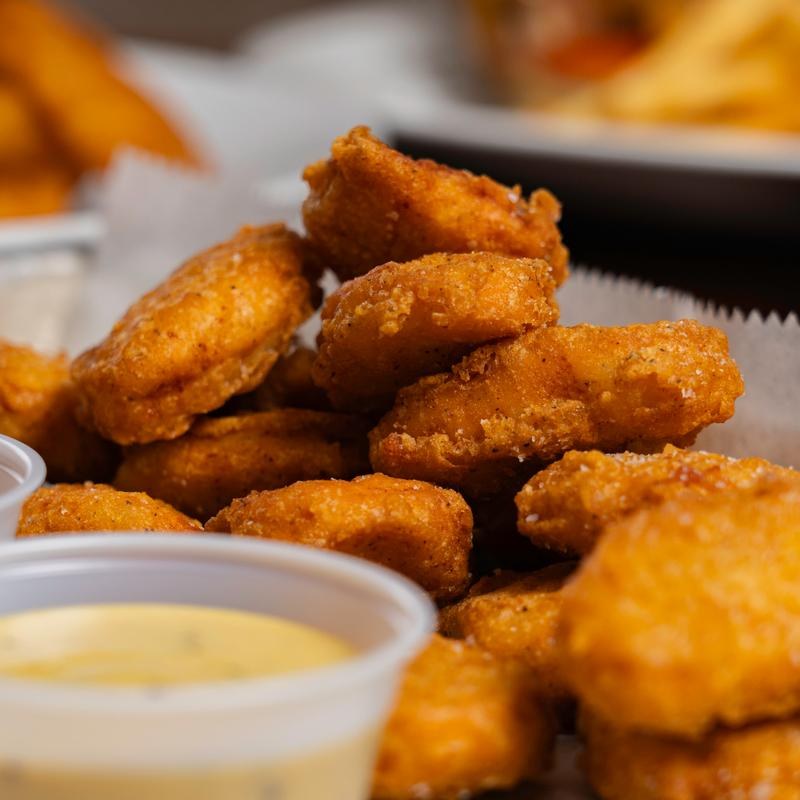 A pile of golden chicken nuggets with a cup of dipping sauce at Amici Tavern in North Haven