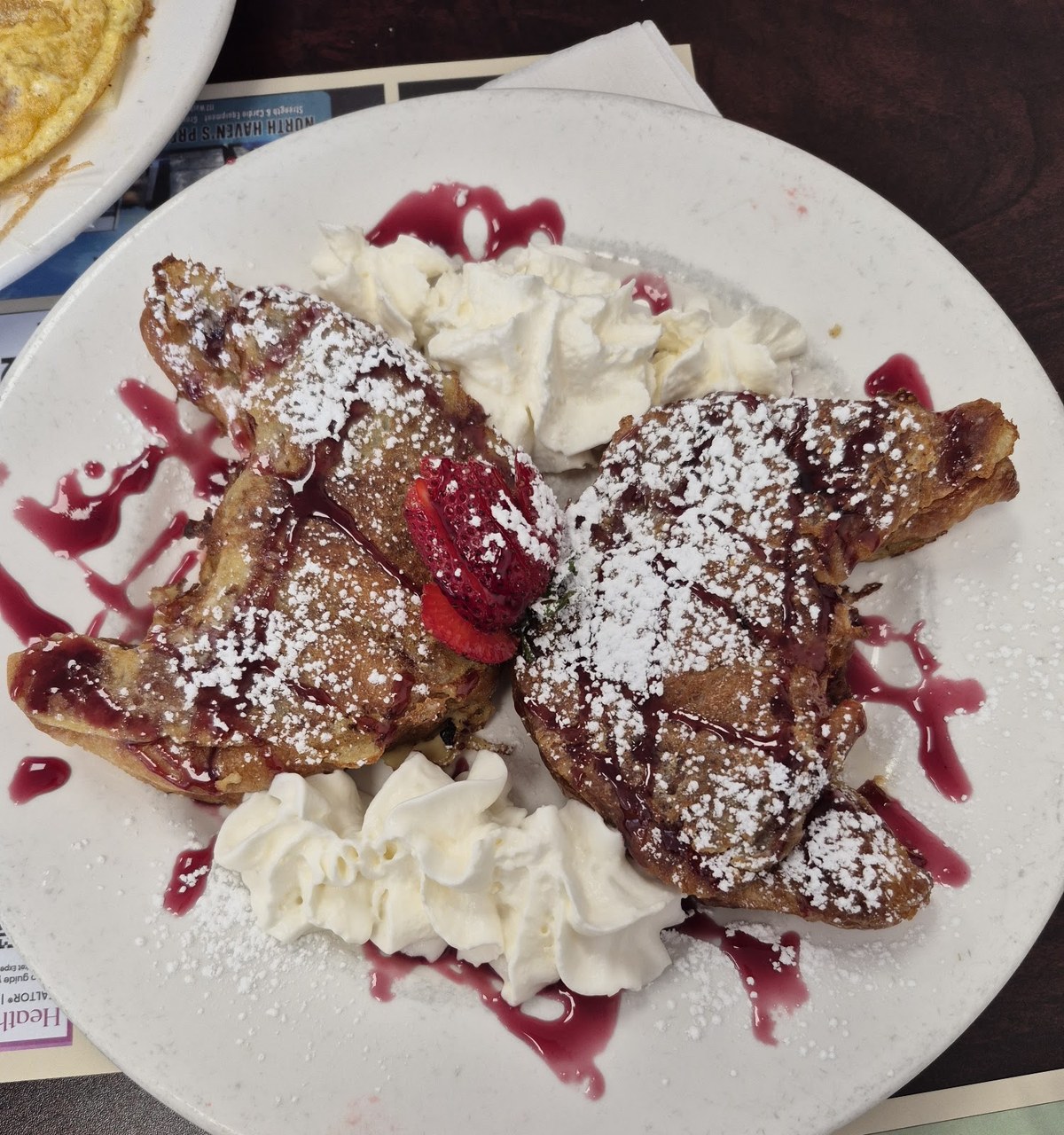 French toast dusted with powdered sugar, with whipped cream and a berry sauce, at Crazy Toast House