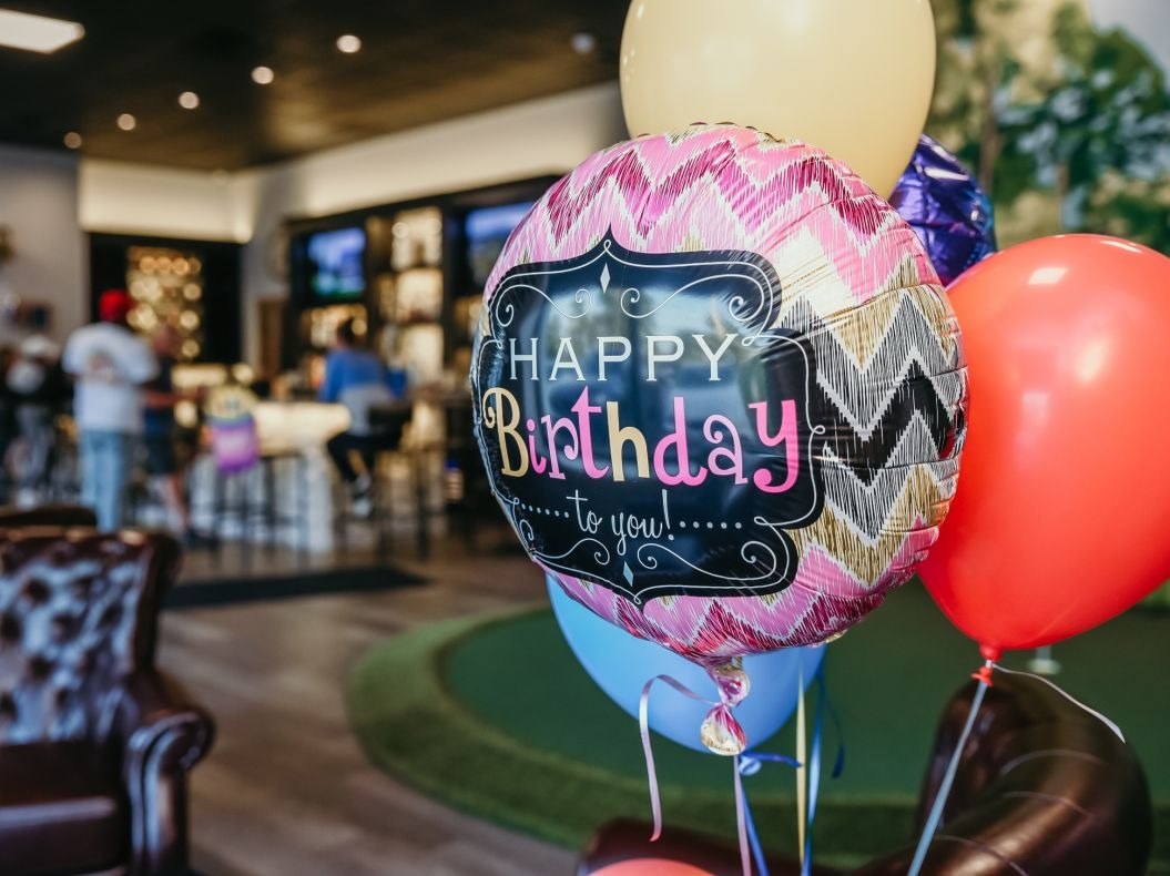 Guests at a birthday party at Golf Cove in North Haven with balloons near a simulator room