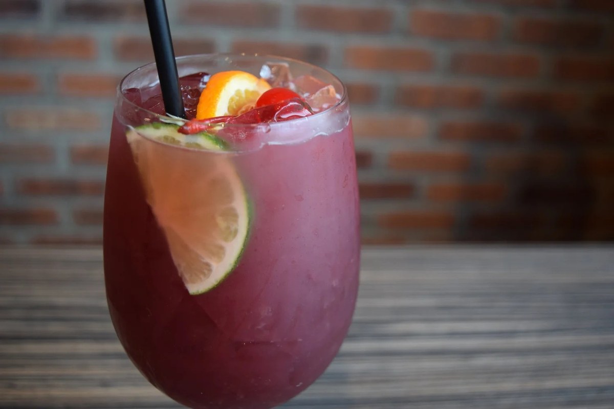 A glass of red sangria with an orange slice and a cherry at J Roo’s