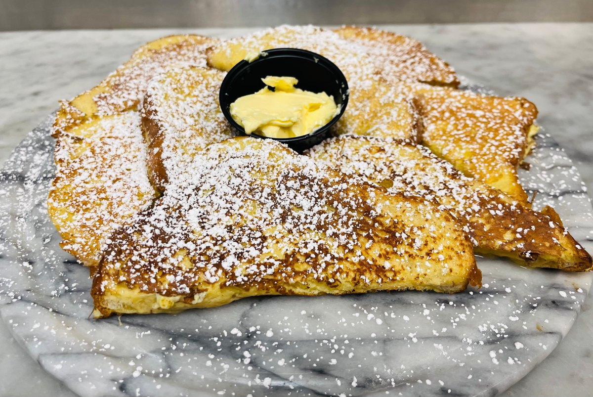 Brioche-style French toast dusted with powdered sugar and served with butter at Sam's Place