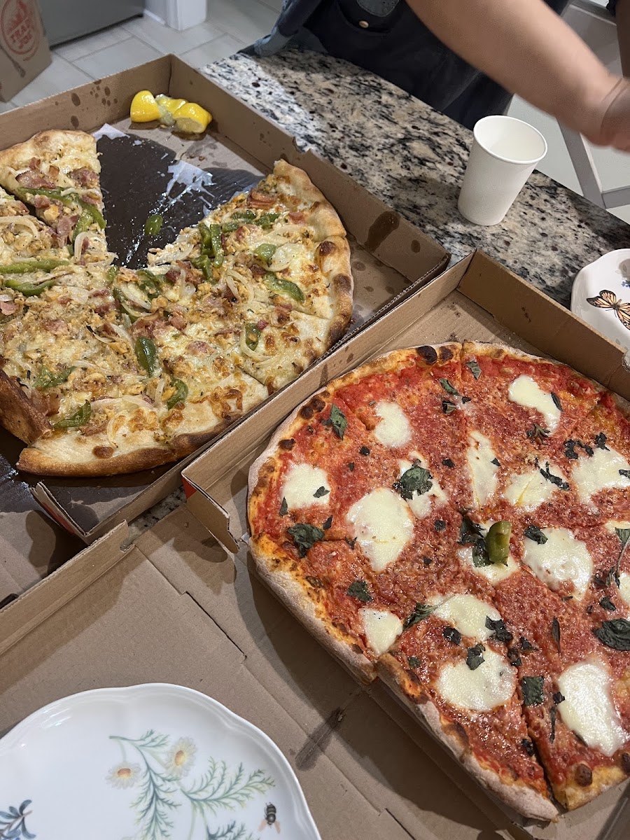 A Margherita pie and a white pie in takeout boxes from Venezia Pizza